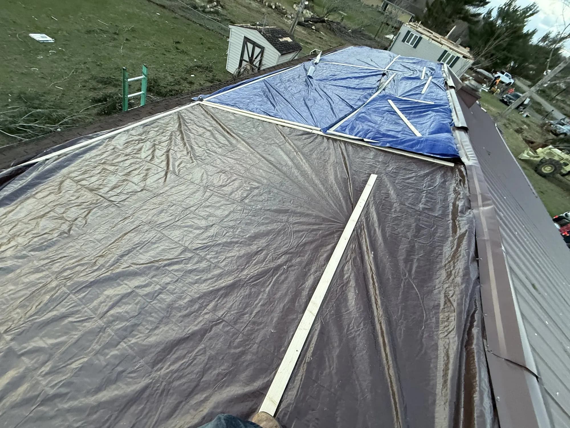 Storm-tarped residential roof with chimney.
