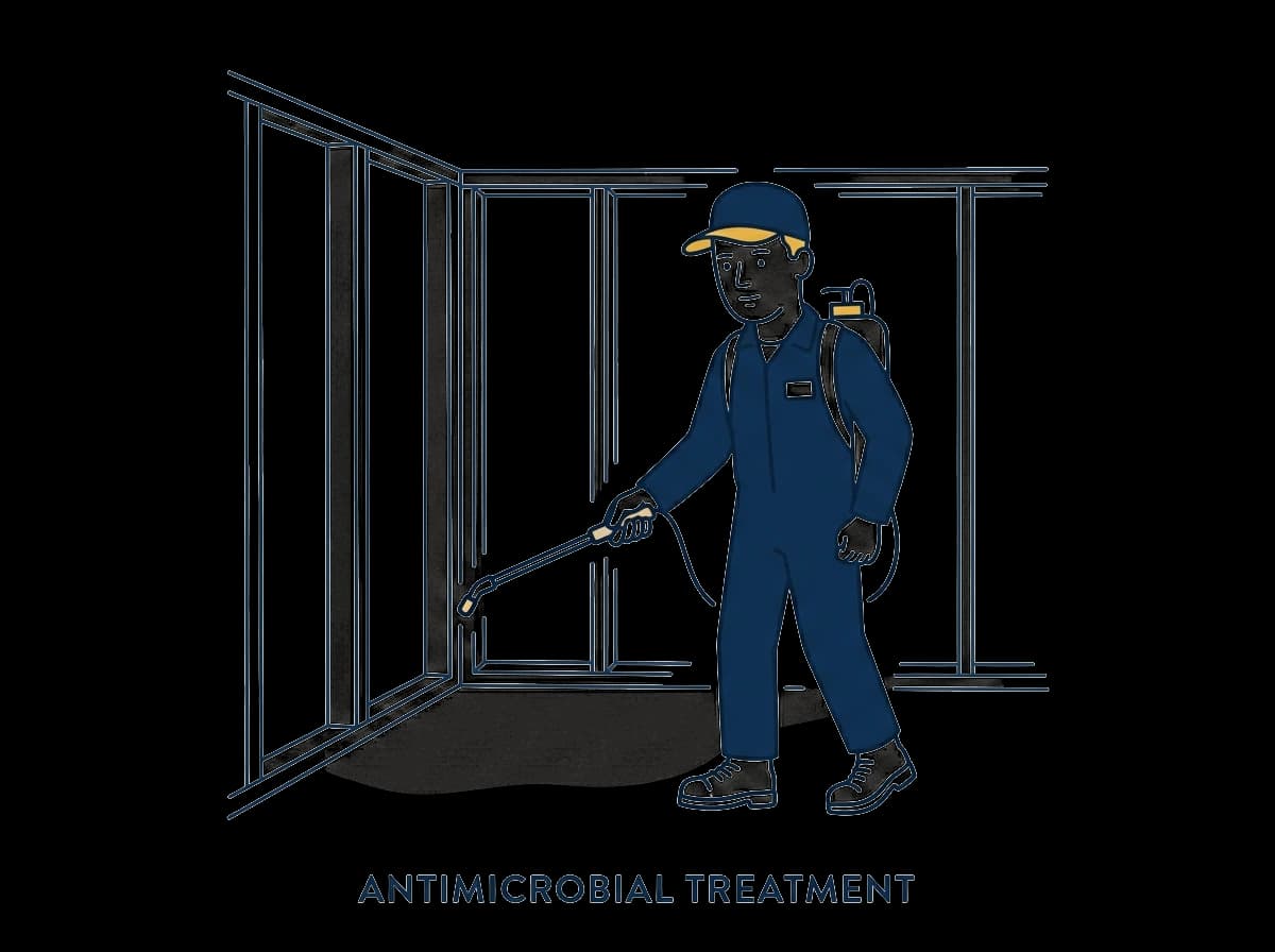 Worker applying antimicrobial spray to exposed studs and subfloor.